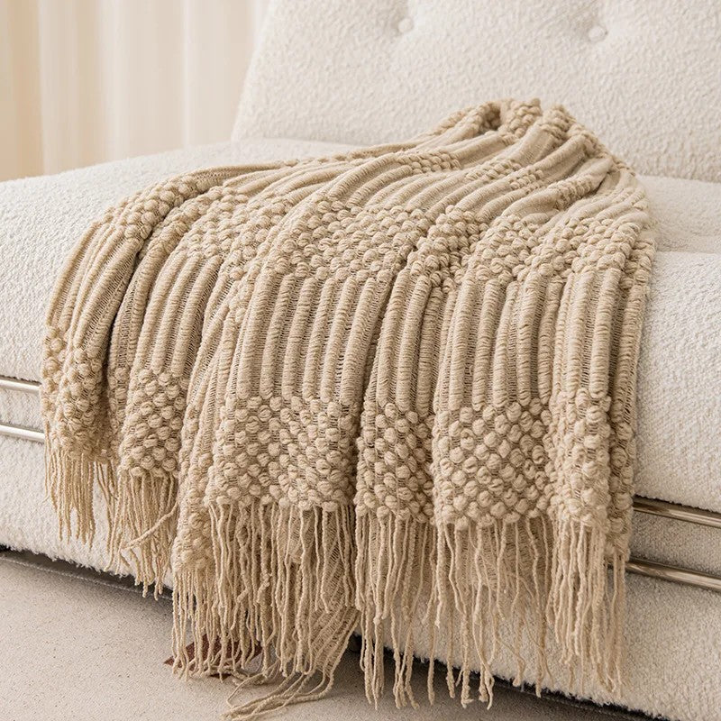 Plaid tricot relief à franges posé sur un canapé